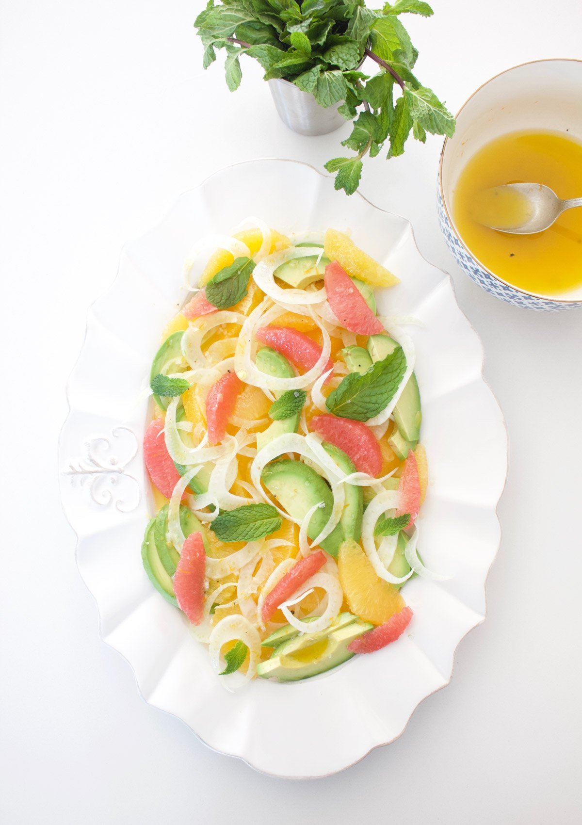 Citrus and avocado salad with a bowl of dressing on the side