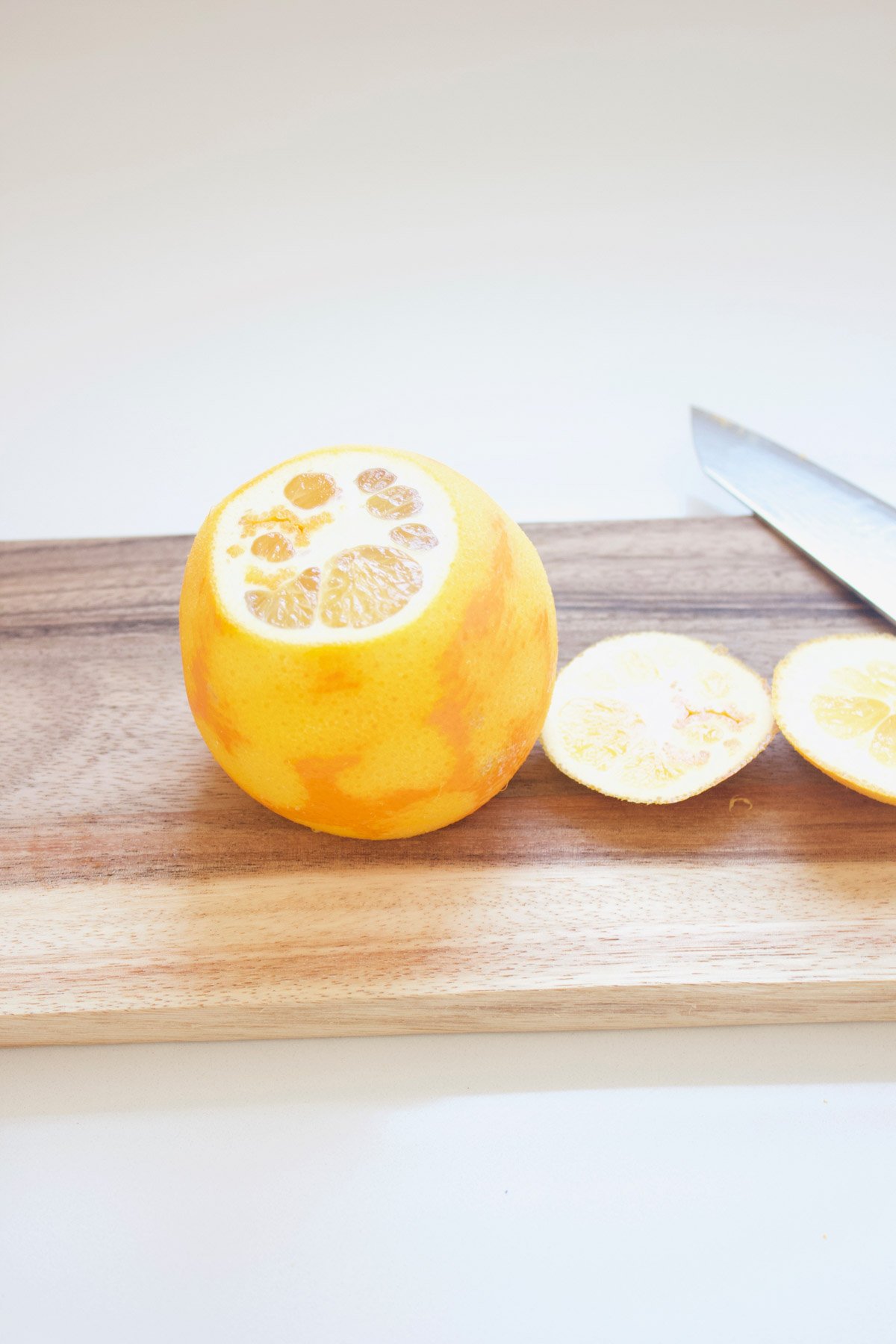 Orange with the end cut off on a cutting board.