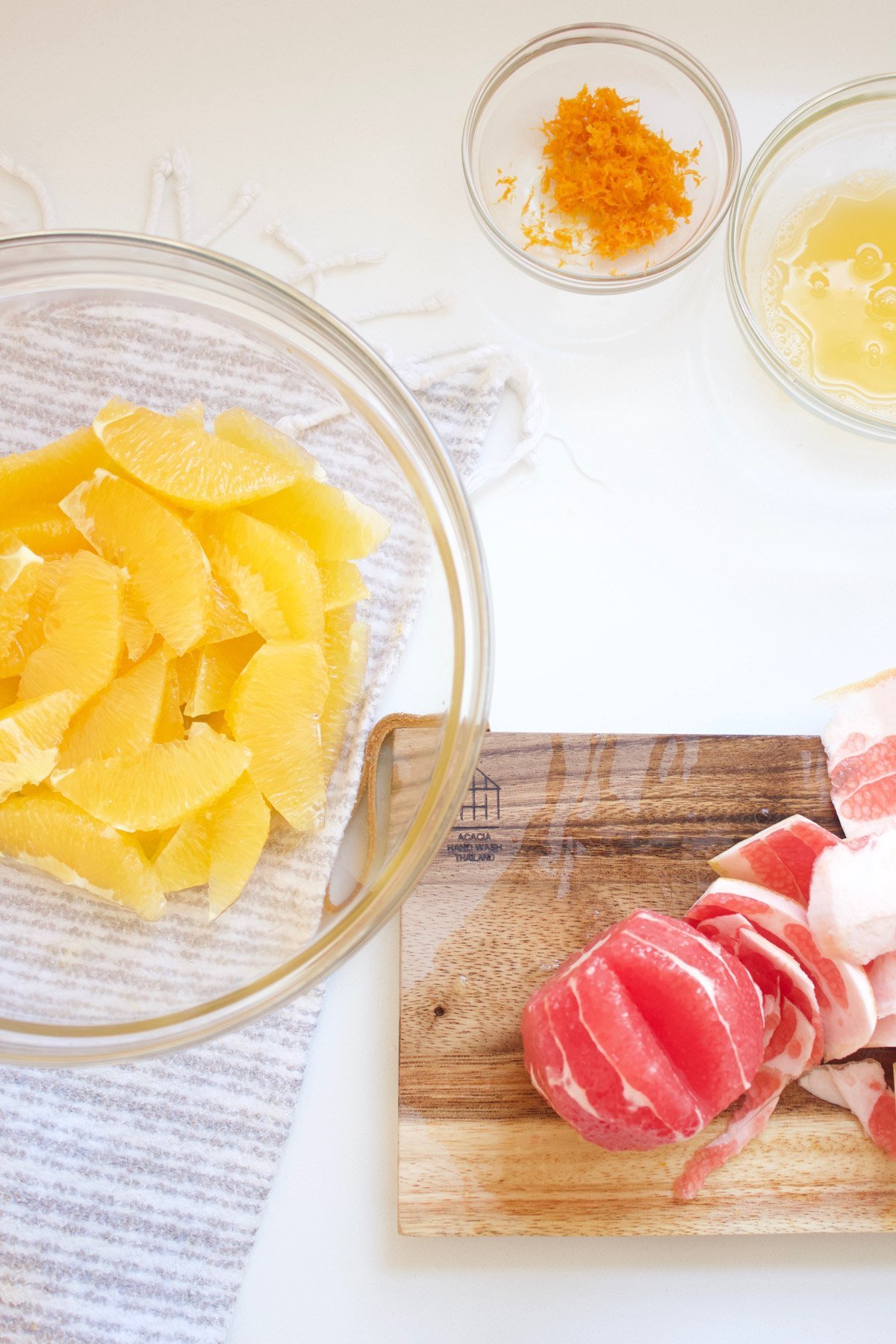 Citrus fruit segments in a bowl with small bowl of orange zest on the side.