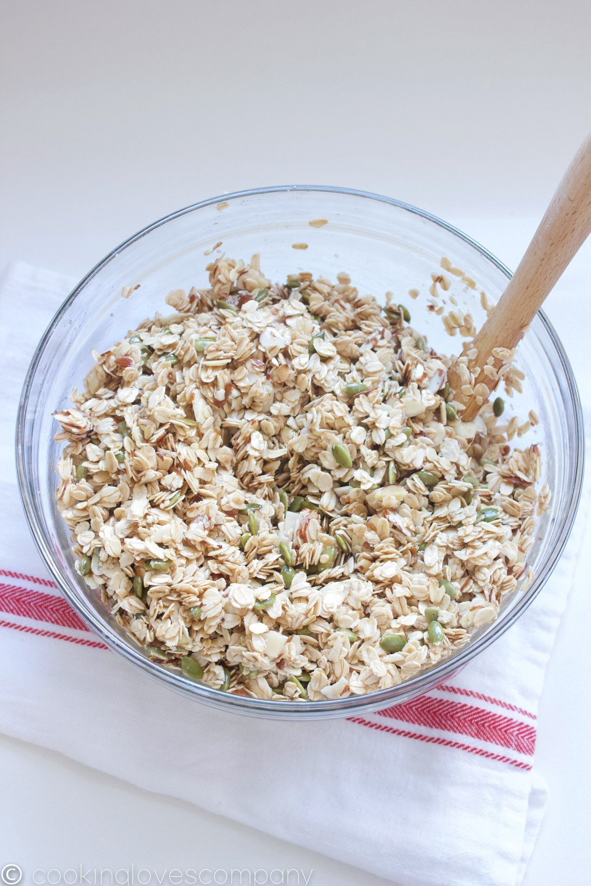 Mixed coconut, maple granola in a bowl with a spatula