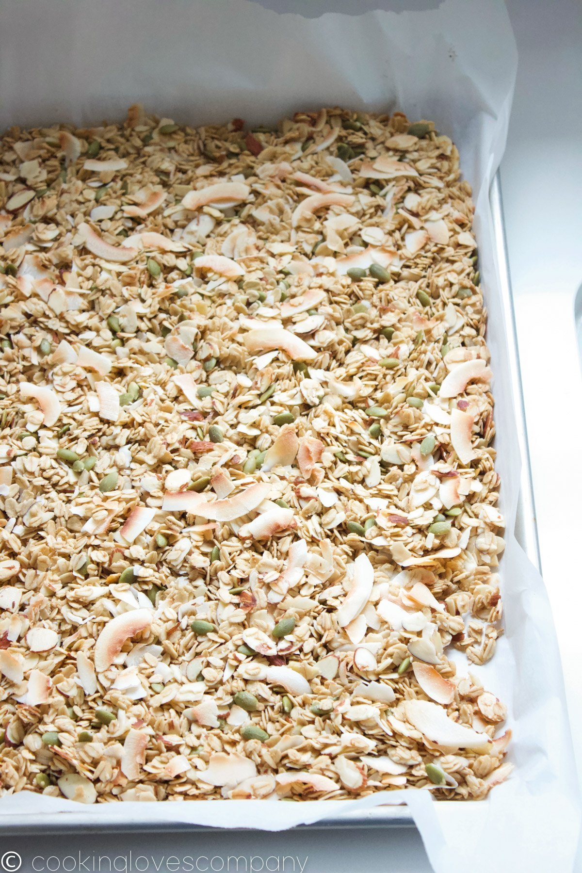Baked coconut, maple granola on a sheet pan lined with parchment paper