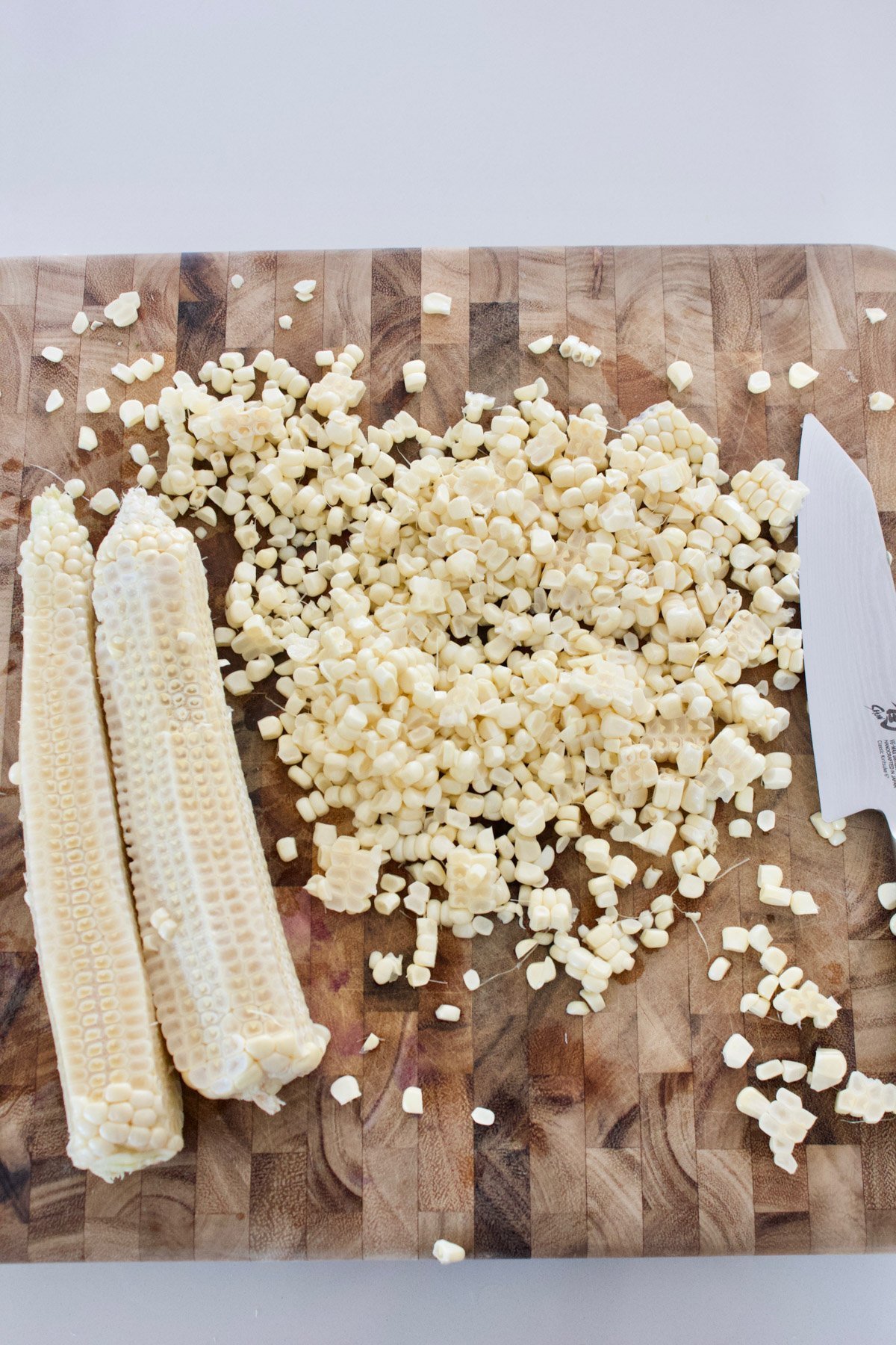Fresh corn cut off a cob on a cutting board. 