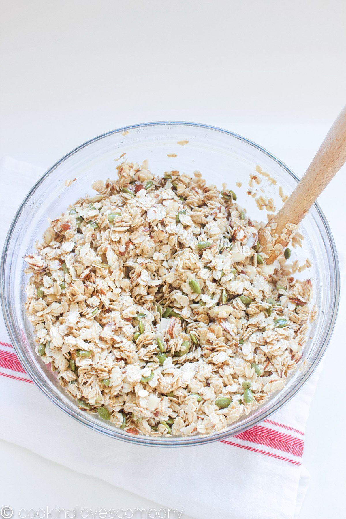 Mixed coconut, maple granola in a bowl with a spatula