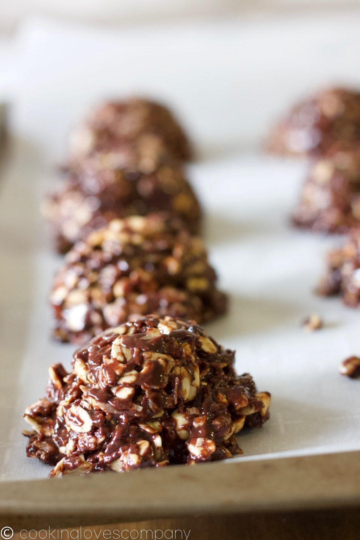 A close up shot of a batch of chocolate oatmeal cookies on a baking sheet