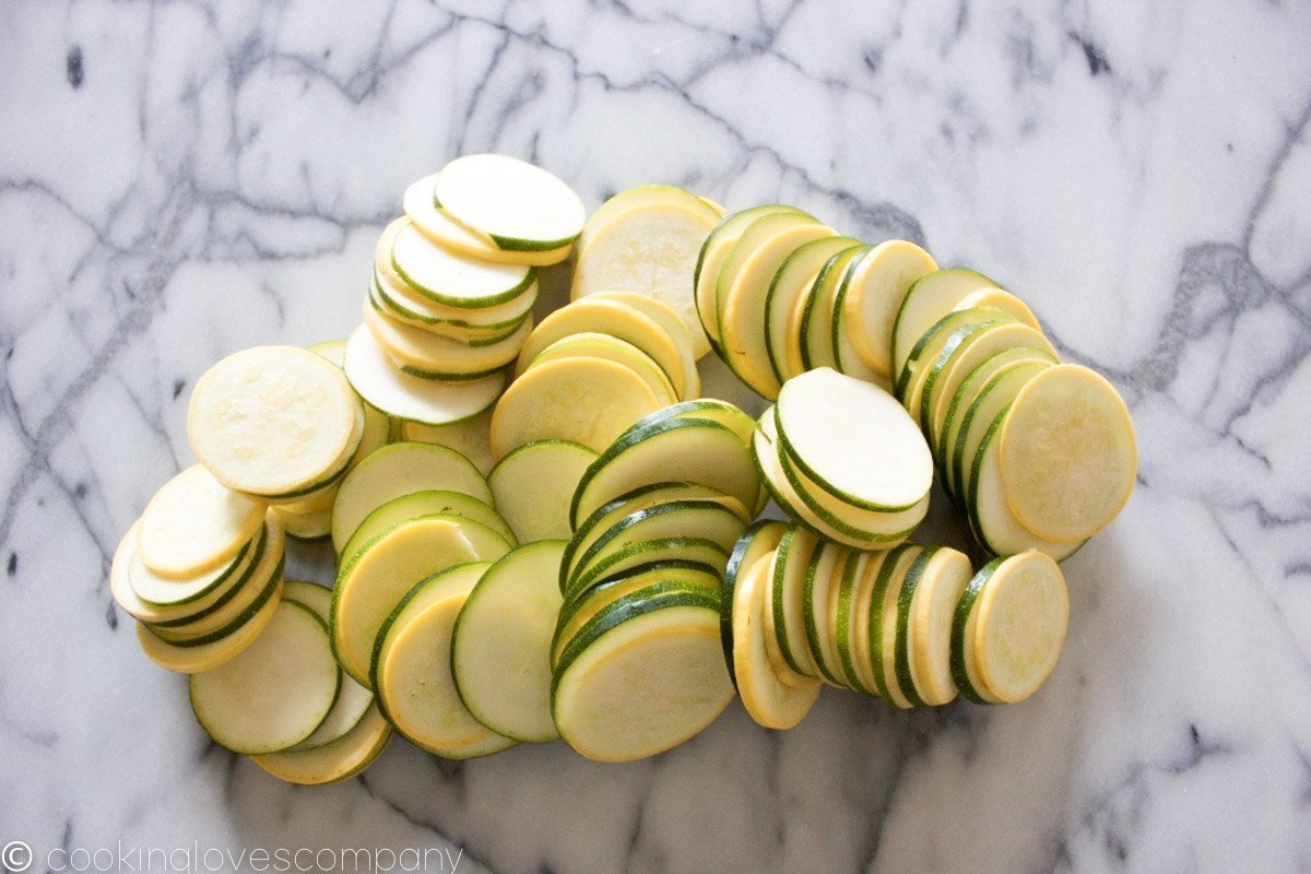 A pile of thinly sliced summer squash on a marble counter