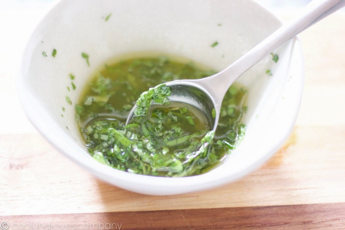 Herb vinaigrette in a small white bowl with a spoon