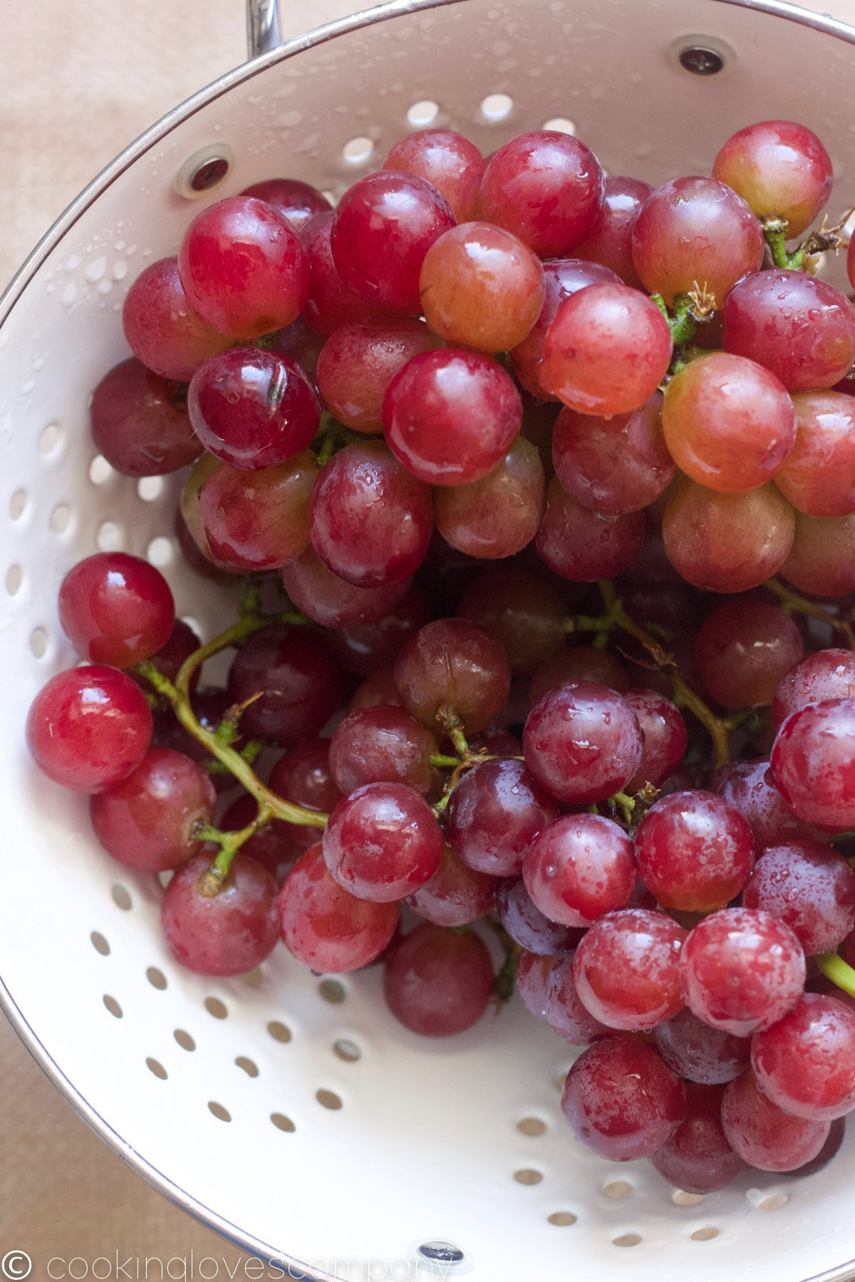 A close up shot of bunch of red grapes in a white colander.