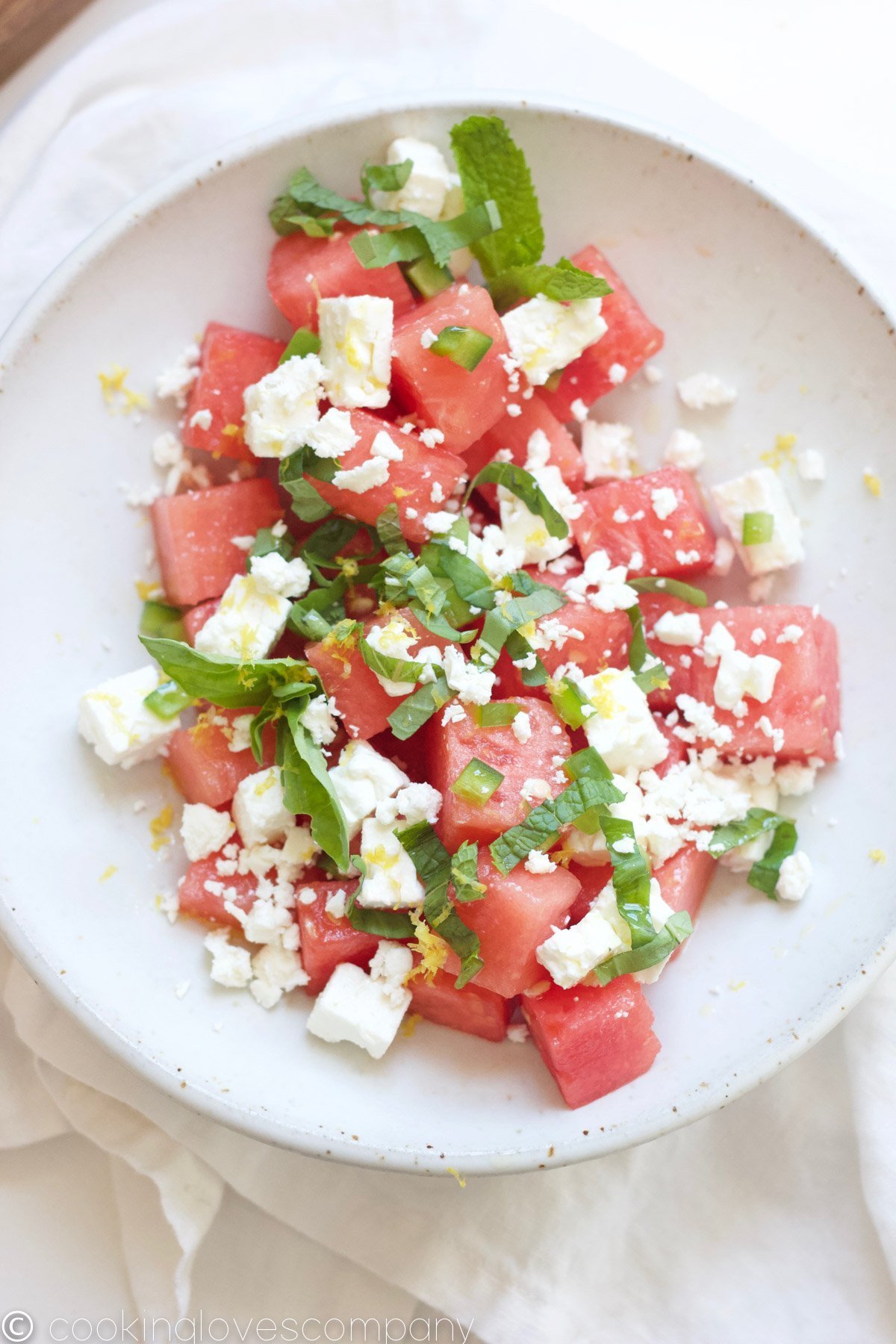 Overhead shot of a watermelon and feta salad with basil and mint in a bowl
