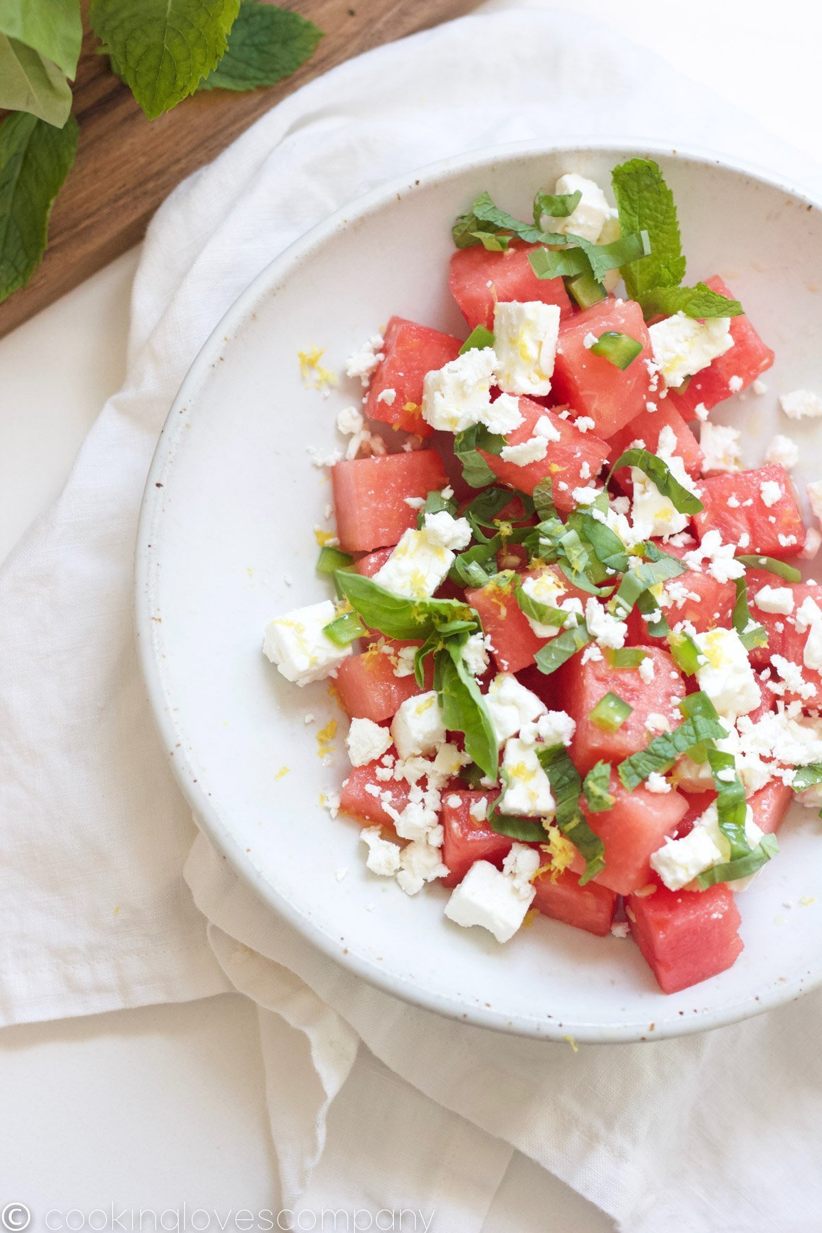 Overhead shot of a watermelon and feta salad with basil and mint in a bowl