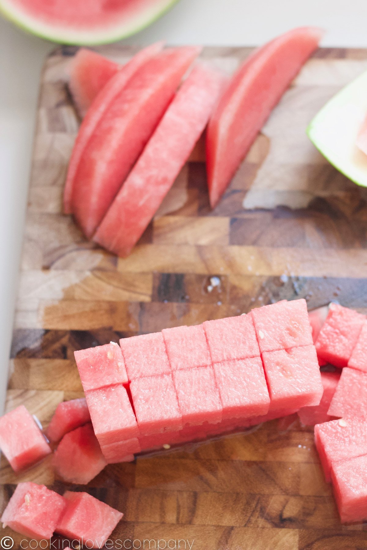 Overhead shot of sliced and cubed watermelon on a wooden cutting board