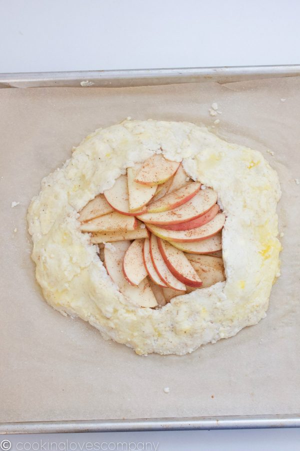 Raw apple galette on a parchment lined baking sheet