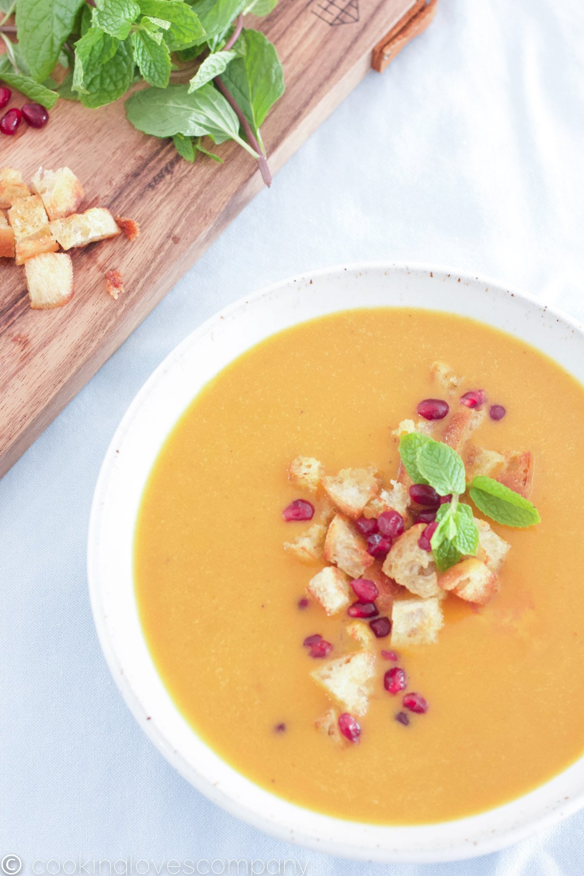 Bowl of pumpkin curry soup with croutons and pomegranate seeds