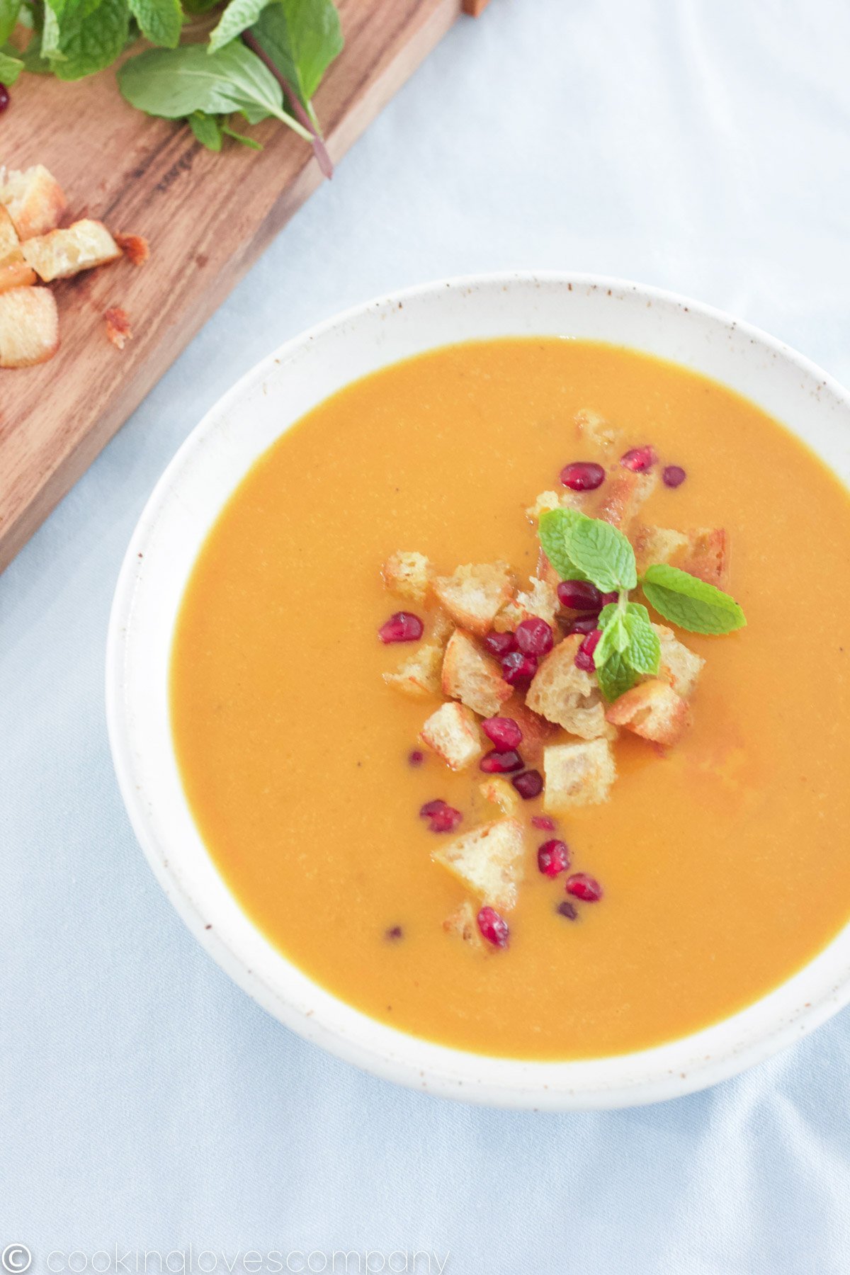 Bowl of pumpkin curry soup with croutons and pomegranate seeds