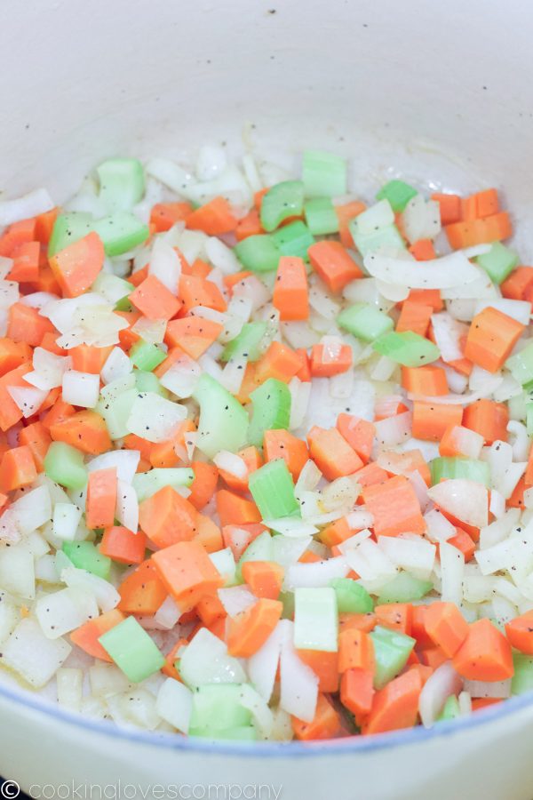 Close up of dutch oven with diced carrots, celery and onion