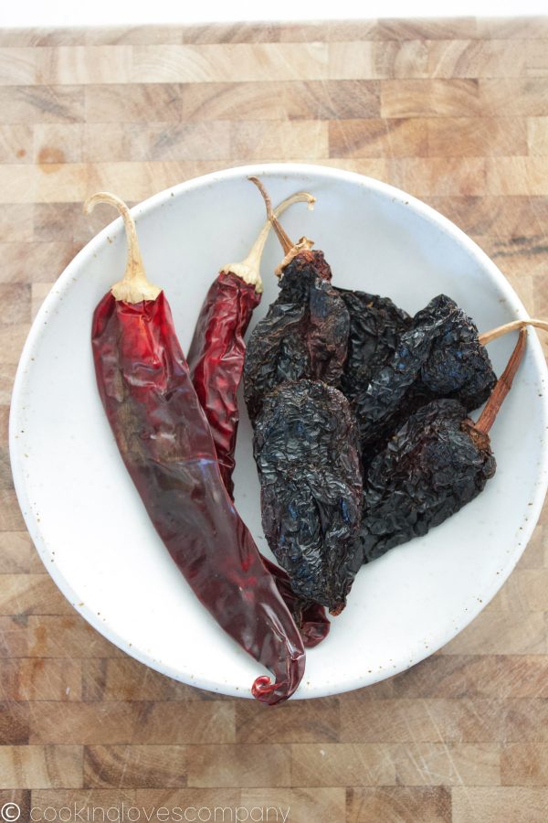 Dried chiles in a bowl on a cutting board