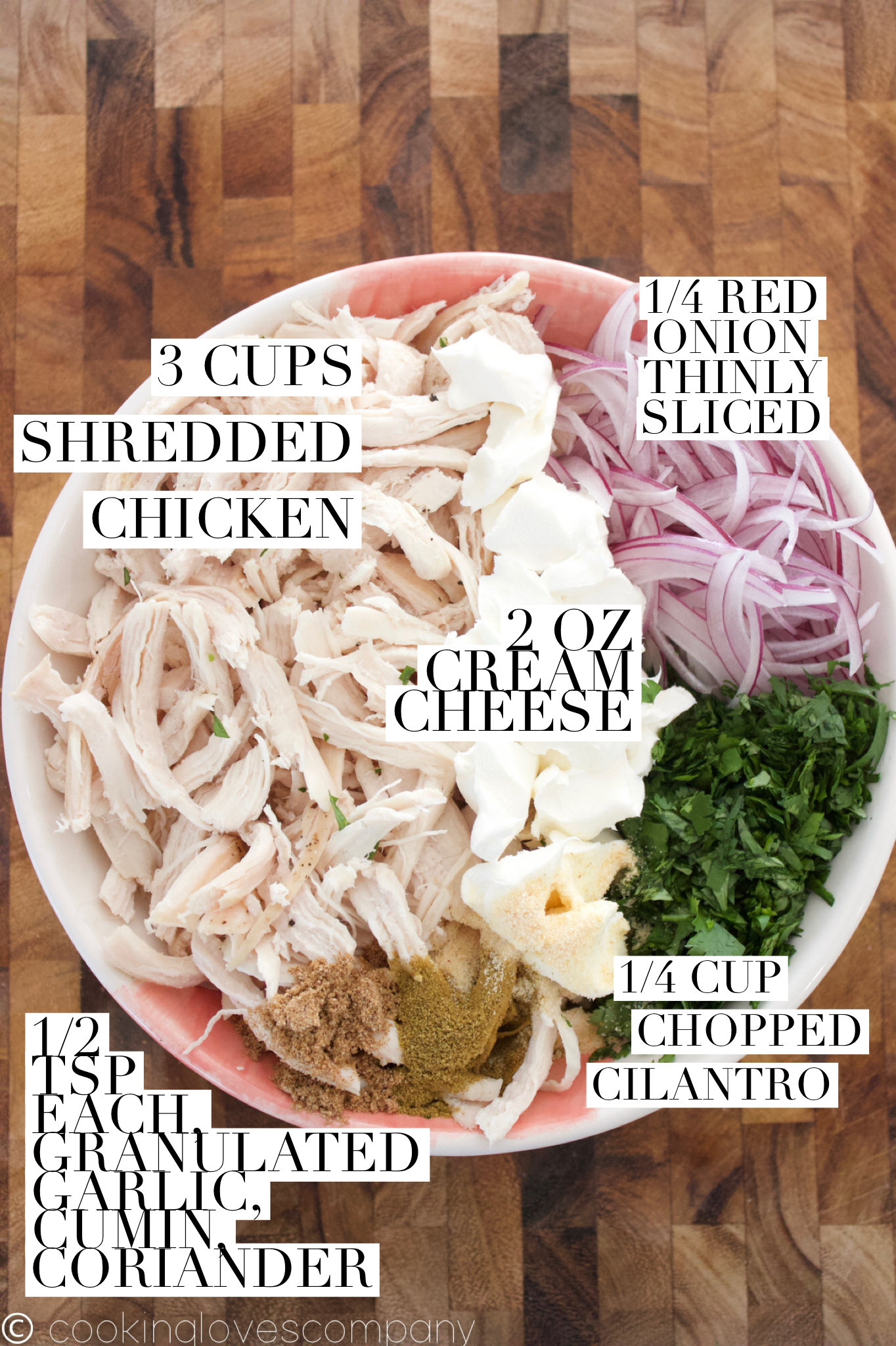 Medium bowl filled with shredded chicken, red onion, cream cheese, cilantro, granulated garlic, cumin and coriander