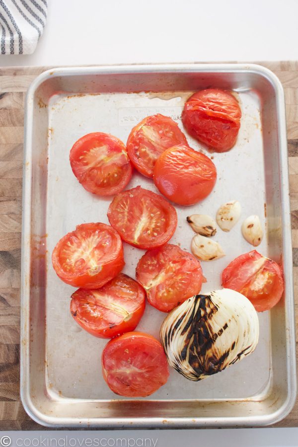 Charred tomatoes, onions and garlic on a sheet pan