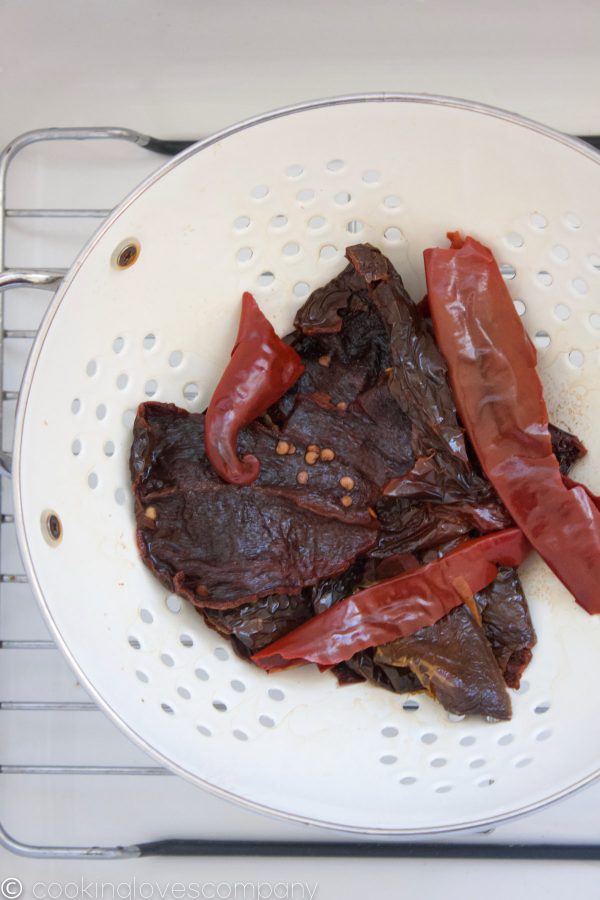 Boiled red chiles in a colander in a sink