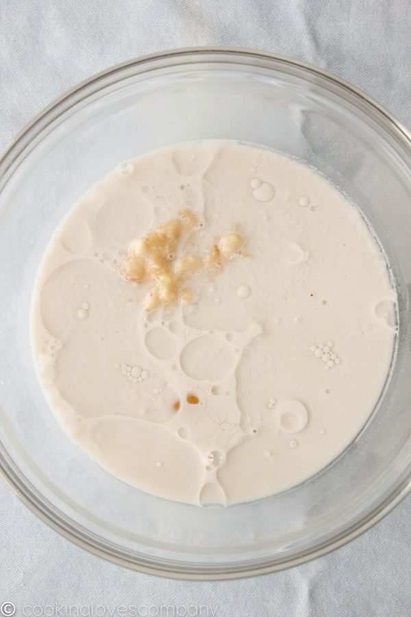A glass bowl filled with almond milk and mashed banana