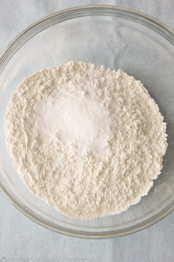 A glass mixing bowl with flour and salt