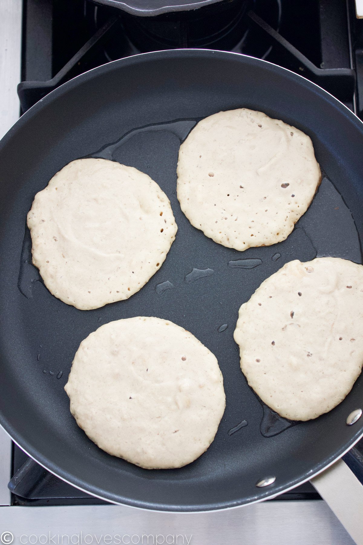 4 pancakes cooking in a non-stick skillet