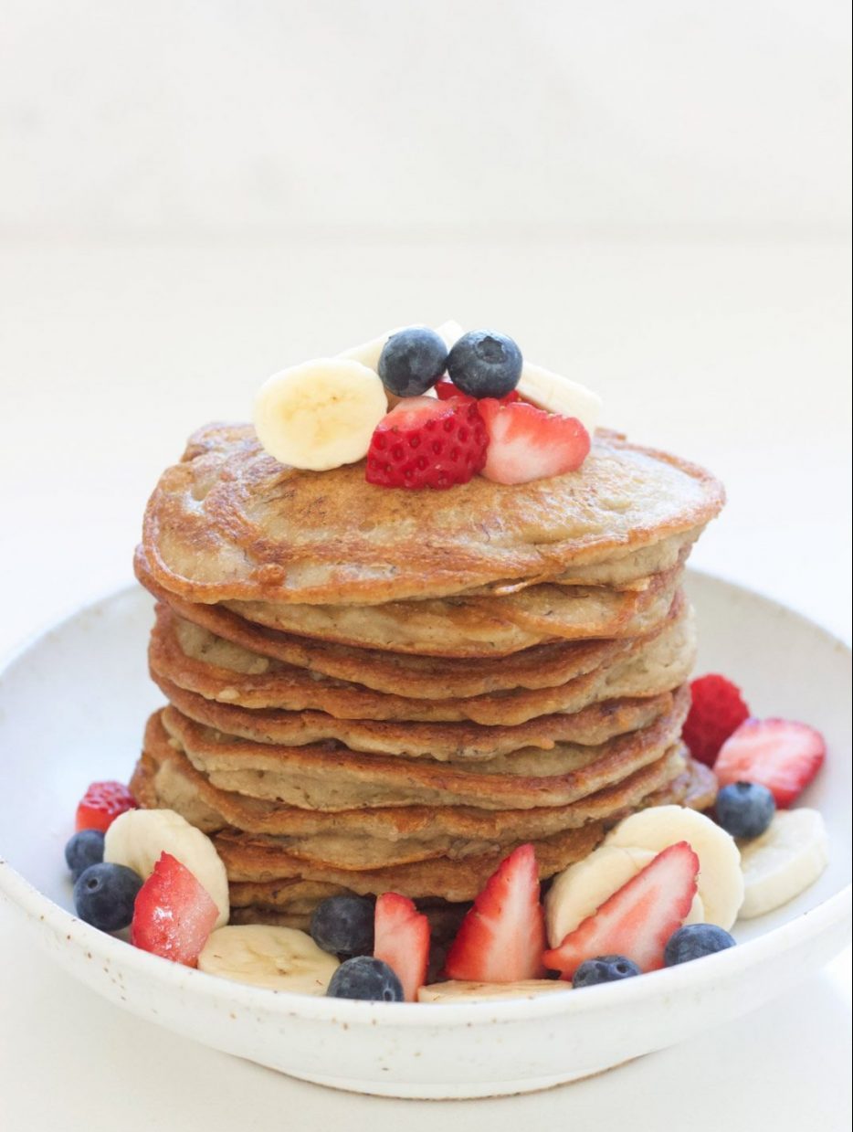 A side angle shot of a stack of banana pancakes with fresh berries